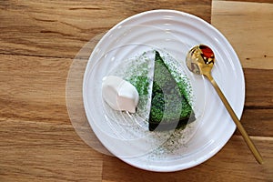 Top view Matcha green tea cake with whipping cream in the white plate on wooden table background. Japanese dessert concept