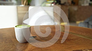 Top view of matcha green tea latte with a latte heart art on wooden table cafe background