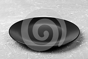 Top view of matte round empty black plate on grey cement background copy space for you design. Perspective view