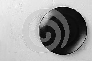 Top view of matte round empty black plate on grey cement background space for you design