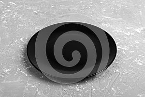 Top view of matte round empty dark dish on dark cement background copy space for you design. Perspective view