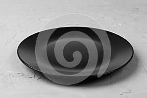 Top view of matte round empty dark dish on grey cement background copy space for you design. Perspective view