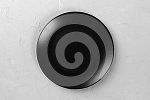 Top view of matte round empty dark dish on grey cement background space for you design