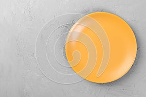 Top view of matte round empty orange plate on dark cement background space for you design