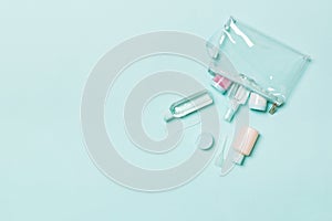 Top view of means for face care: bottles and jars of tonic, micellar cleansing water, cream, cotton pads on blue background.