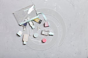 Top view of means for face care: bottles and jars of tonic, micellar cleansing water, cream, cotton pads on gray background.