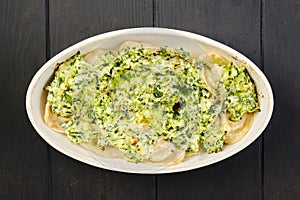 Top view of meat dumplings with spinach and cheese sauce baked in oven