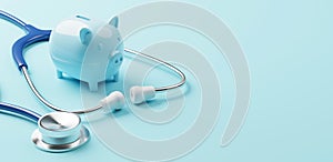 Top view of medical stethoscope and piggy bank on cyan background