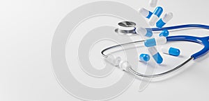 Top view of medical stethoscope and pill capsule falling on white background