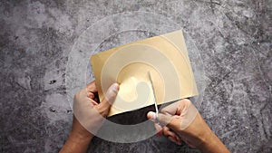top view of mens hand cutting a blank paper on table