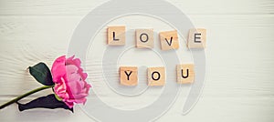 Top view Message I love you spelled in wooden blocks with pink peony flower on white wooden table. Love, Valentines day background