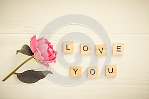 Top view Message I love you spelled in wooden blocks with pink peony flower on white wooden table. Love, Valentines day background