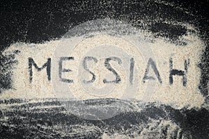 Top view of MESSIAH word written on white sand