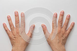 Top view of middle aged woman hands with cut and uncoloured nails on the white background