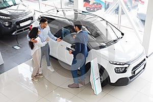 Top view of middle eastern couple choosing auto at showroom