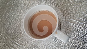 Top view of milk black tea in a ceramic cup placed over a mat sheet