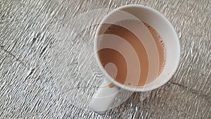 Top view of milk black tea in a ceramic cup placed over a mat sheet