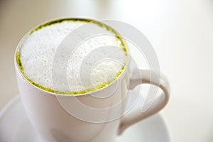 Top view of milk green tea matcha latte with the saucer on white table background. Hot milk green tea (selective focus)