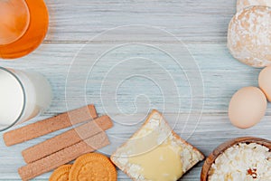 top view of milk products as milk cottage cheese smeared on bread slice with cookies butter gingerbreads eggs on wooden background
