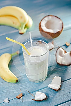 Top view of milkshake with coconut milk and bananas on white wooden table. Selective focus. Tropical