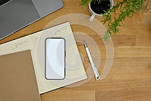 Top view, Minimal wood tabletop workspace with smartphone mockup, pen, notepad, laptop