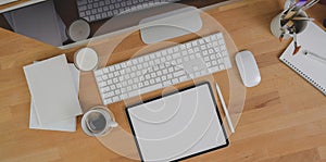 Top view of minimal workplace with blank screen tablet, desktop computer and office supplies