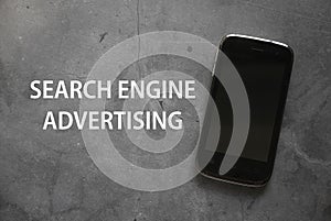 Top view of a mobile phone on grey background written with Search Engine Advertising