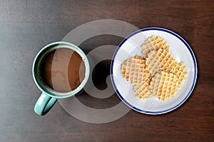 Top view mocha coffee in green cup and many waffle on dish on wooden table