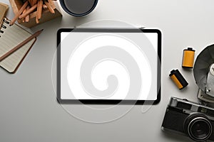 Top view of digital tablet with empty screen, notebook, camera and coffee cup on photographer workplace.