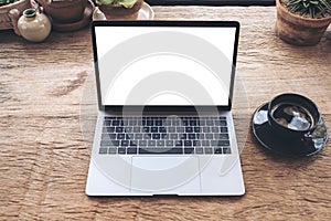 Top view mockup image of laptop with blank white desktop screen and coffee cup on vintage wooden table