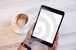 Top view mockup image of a woman`s hands holding black tablet pc with blank white screen