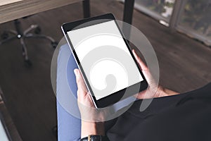 Top view mockup image of a woman sitting cross legged and holding black tablet pc with blank desktop screen