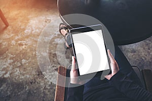 Top view mockup image of a woman sitting cross legged and holding black tablet pc with blank white desktop