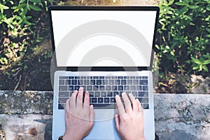 Top view mockup image of a woman using and typing on laptop with blank white desktop screen , sitting at outdoor