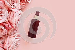 Top view of mockup of unbranded brown plastic spray bottle and pink roses on a pastel pink background. Natural organic spa