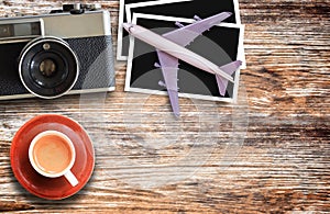 Top view with model plane,retro camera and cup of coffee on wooden table background