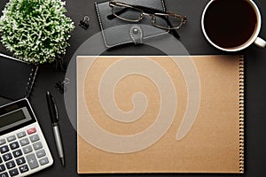 Top view of modern black office desk with blank paper sheet, notebook, pen and a lot of things. Flat lay table layout. Copy space