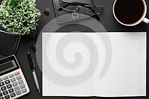 Top view of modern black office desk with blank paper sheet, notebook, pen and a lot of things. Flat lay table layout. Copy space