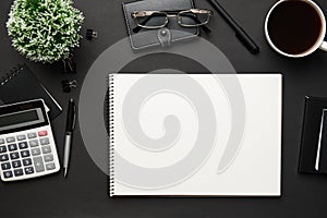 Top view of modern black office desk with blank paper sheet, notebook, pen and a lot of things. Flat lay table layout. Copy space