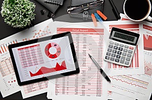 Top view of modern black office desk with tablet pc and financial reports, notebook, pencil and a lot of things. Flat lay table