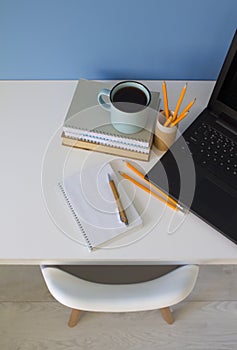 Top view on modern creative empty student workspace with white table and chair. Wooden pen with empty grid-lined notebook on white