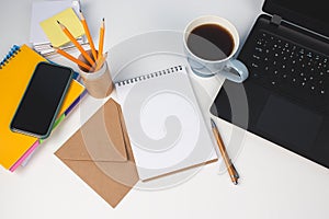 Top view on modern creative enterpreneur workspace. Blue cup of coffee, yellow pencils in reusable paper tube and empty notebook