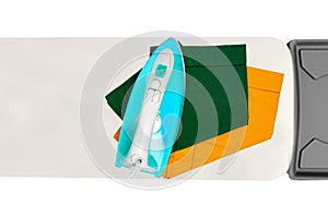 Top view of a modern electric blue iron ironing a green and a yellow cloth napkin on an ironing board indoors isolated.