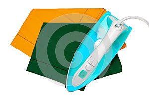 Top view of a modern electric blue iron ironing a green and a yellow cloth napkin isolated on a white background. Housework