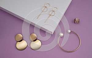 Top view of modern jewelries collection on white podium on purple background