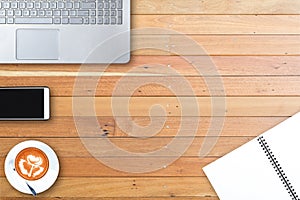 Top view of modern office workplace with computer laptop , smart phone , notebook paper , latte art coffee cup on wooden table