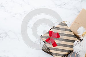 Top view of modern striped present box with red bow lay under white christmas tree on white marble floor,Holiday gift