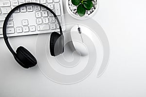 Top view of modern white desk with Headset and computer keyboard on white background.