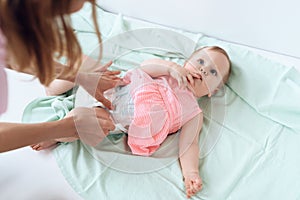 Top view. Mom giving baby diaper change at home.