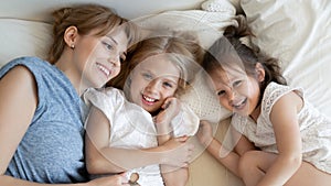 Top view of mom relax in bed with little daughters